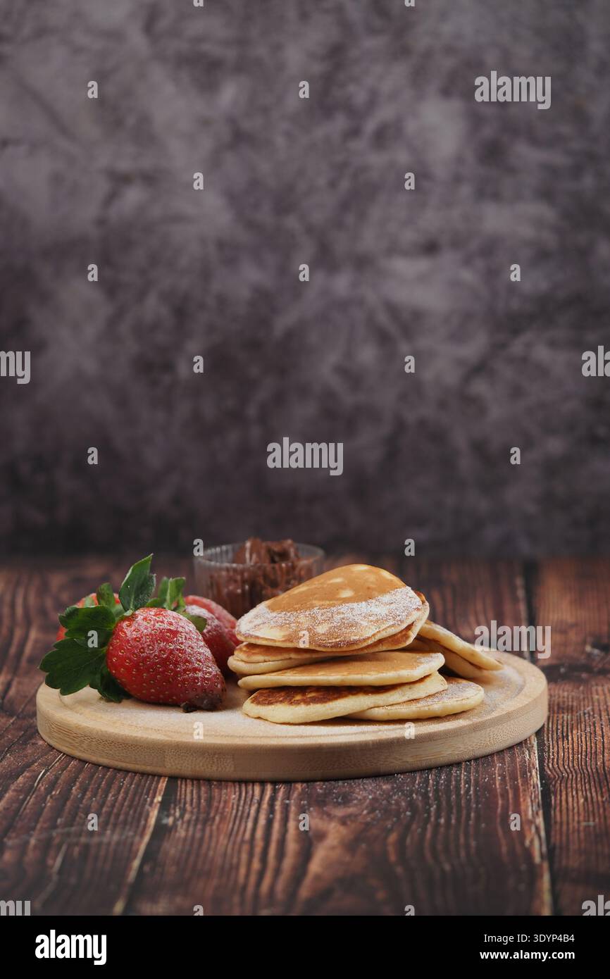 Pfannkuchen mit Erdbeeren und Schokolade auf einem Holztisch Stockfoto