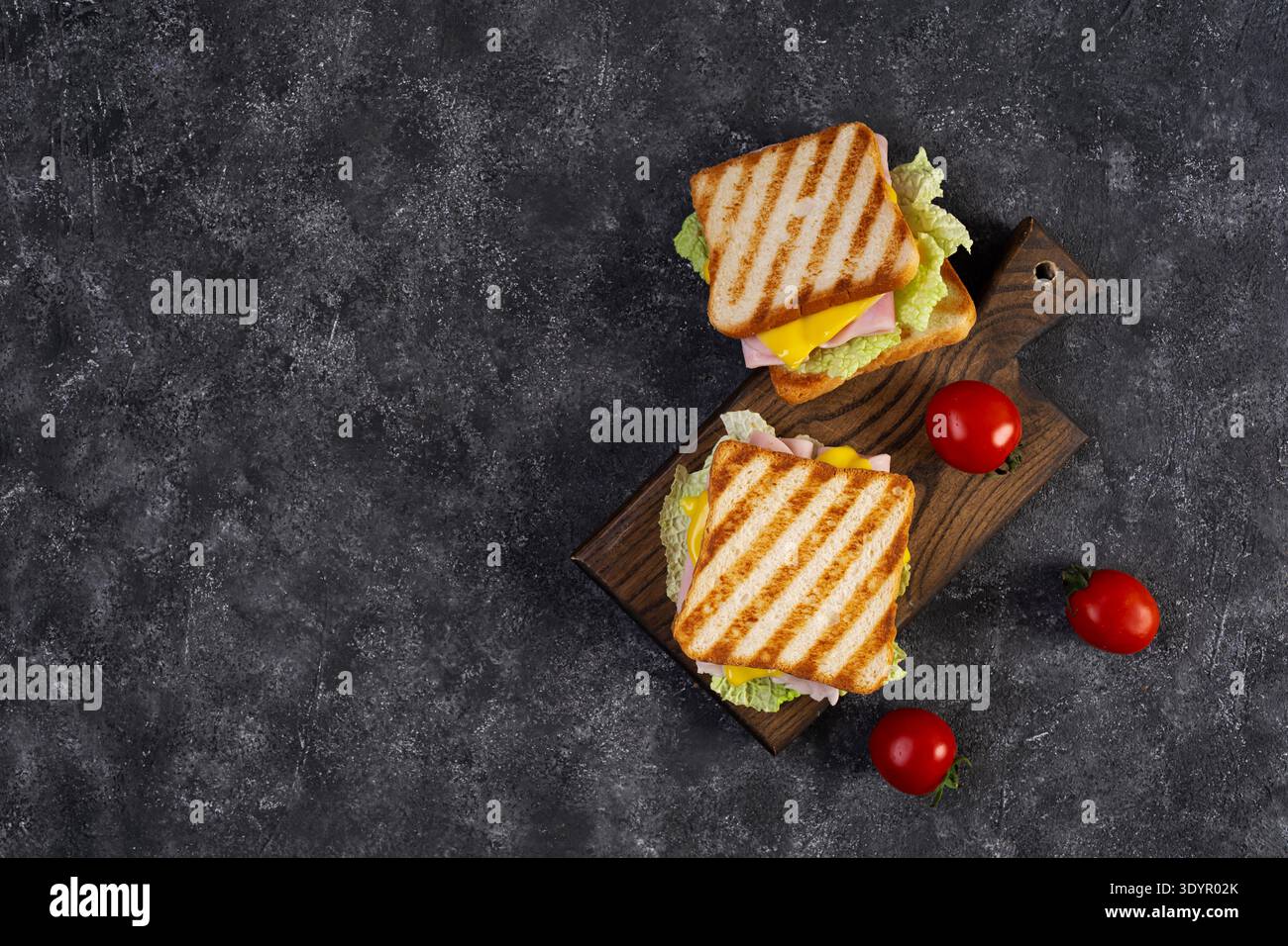 Köstliches Sandwich mit Schinken, Käse, Tomaten und Salat auf geröstetem Brot. Perfekte Idee für ein Mittagessen oder einen Snack Stockfoto