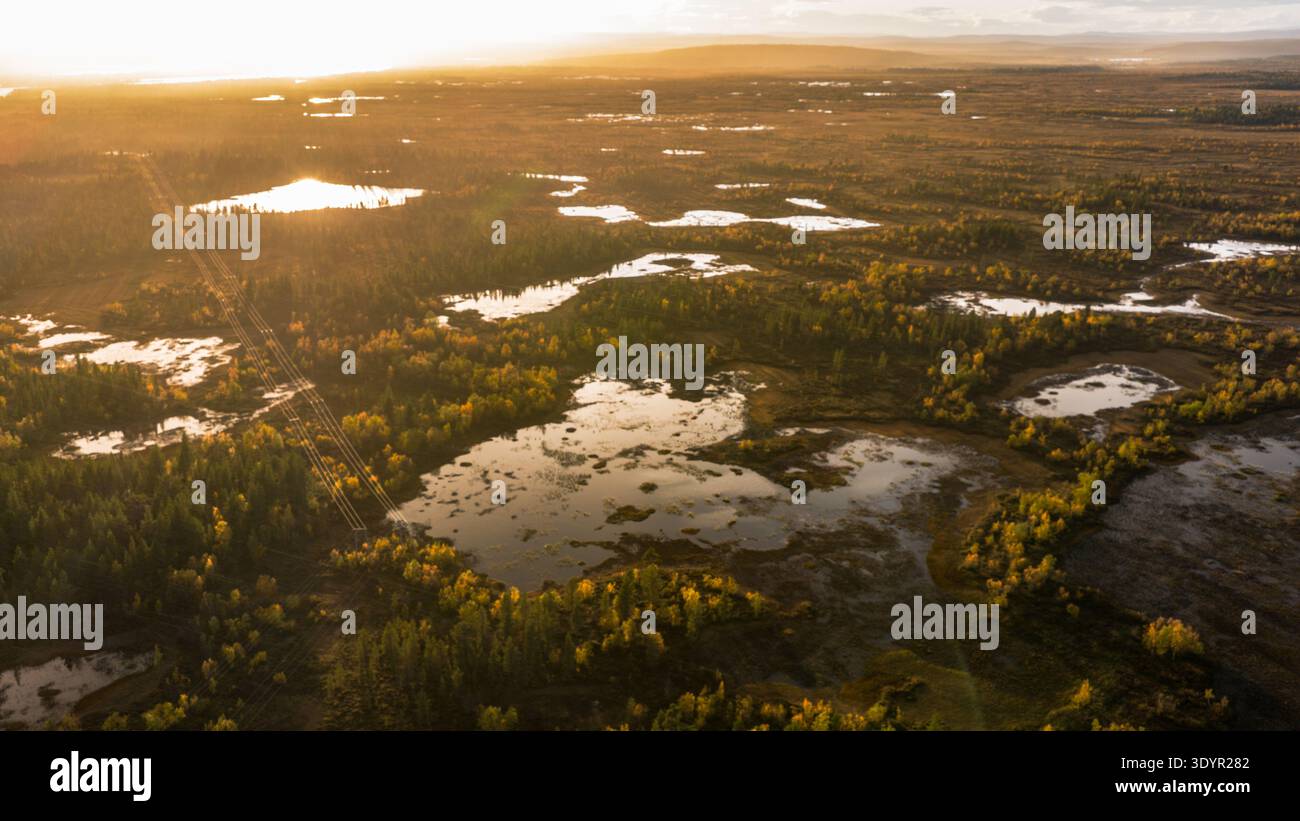 Aus der Vogelperspektive des goldenen Sonnenlichts, das die ruhigen Seen und Wälder küsst und lange Schatten über die beschauliche Landschaft wirft, Enontekiö Kilpisjärvi, Stockfoto