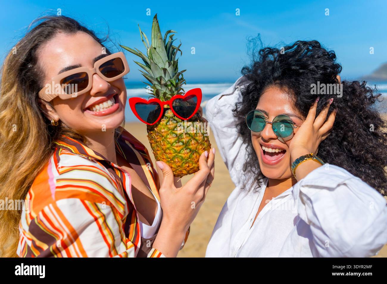 Zwei junge Freunde, die Spaß mit Ananas am Strand haben Stockfoto