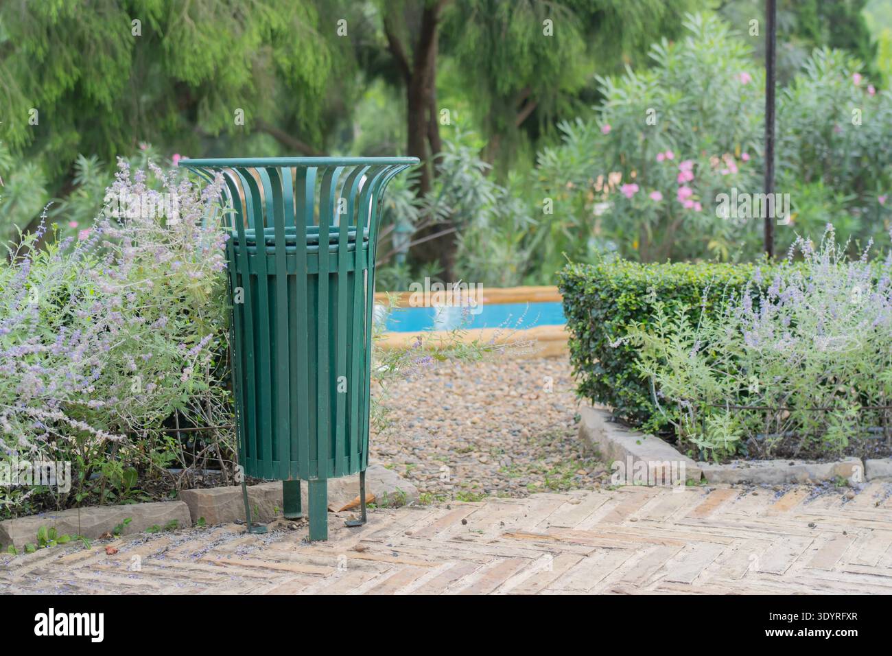Öffentlicher Park im Frühling mit Metallmüll am Eingang zum Swimmingpool in einem wunderschönen Garten. Konzepte zur Umweltreinigung. Stockfoto