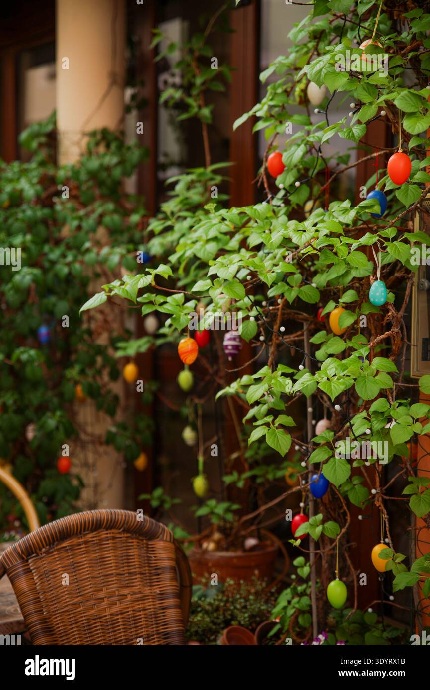 Farbenfrohe Ostereierdekorationen Hängen An Grünen Pflanzenzweigen Auf Der Gemütlichen Terrasse Im Freien Stockfoto