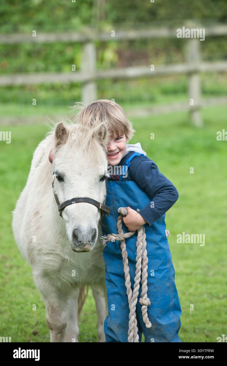 Kinder im Grundschulalter genießen einen lehrreichen Tag in der britischen Landschaft und interagieren eng mit traditionellen landwirtschaftlichen Nutztieren. Die Gruppe wird beobachtet, wie sie Hühner auf einem Bauernhof vorsichtig füttert, die sanfte Natur von weidenden Schafen beobachtet und mehr über Pferdepflege lernt, während sie Pferde und Ponys trifft. Diese überwachten Interaktionen bieten wichtige Lernerfahrungen im Freien und vermitteln Schülern in einer sicheren, praxisnahen Umgebung mehr über das Wohlergehen von Tieren, das ländliche Leben und die Herkunft ihrer Nahrung. Stockfoto