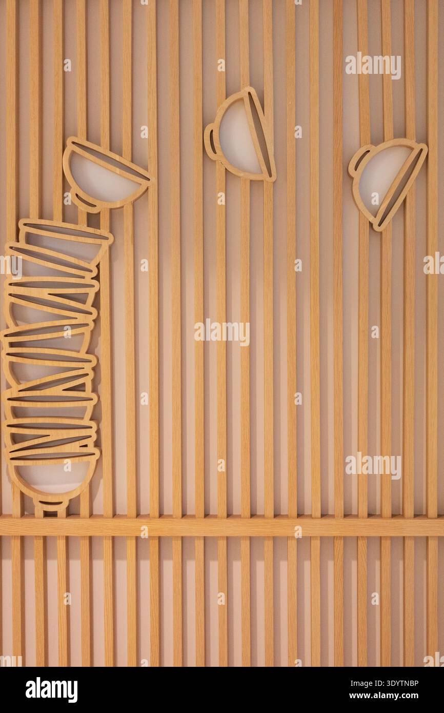 Minimalistische japanische Zen-Wandkunst mit Holzlatten und stilisierten Schüsselausschnitten in hellem Natureichen-Finish in einem Restaurant in Osaka Stockfoto