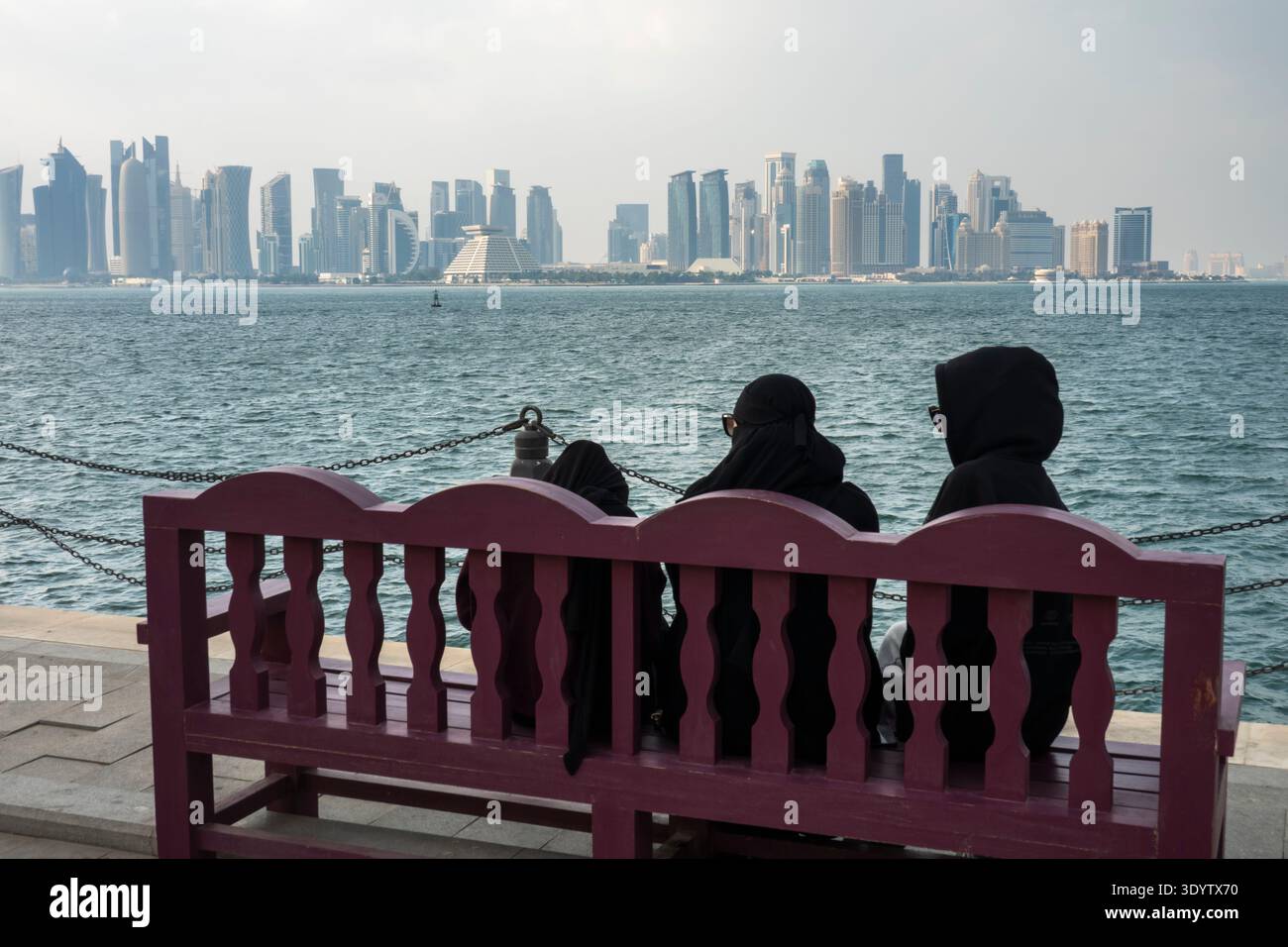 Die Skyline von Doha mit Frauen auf der Bank, die Burka tragen, aus dem Stadtteil Mina, Doha, Katar Stockfoto