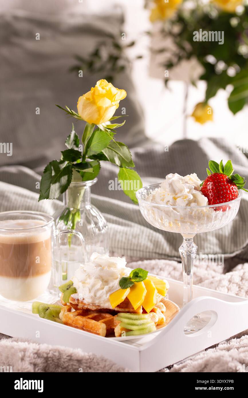 Belgische Waffeln mit Schlagsahne, Obst und Kaffee auf einem Tablett. Stockfoto