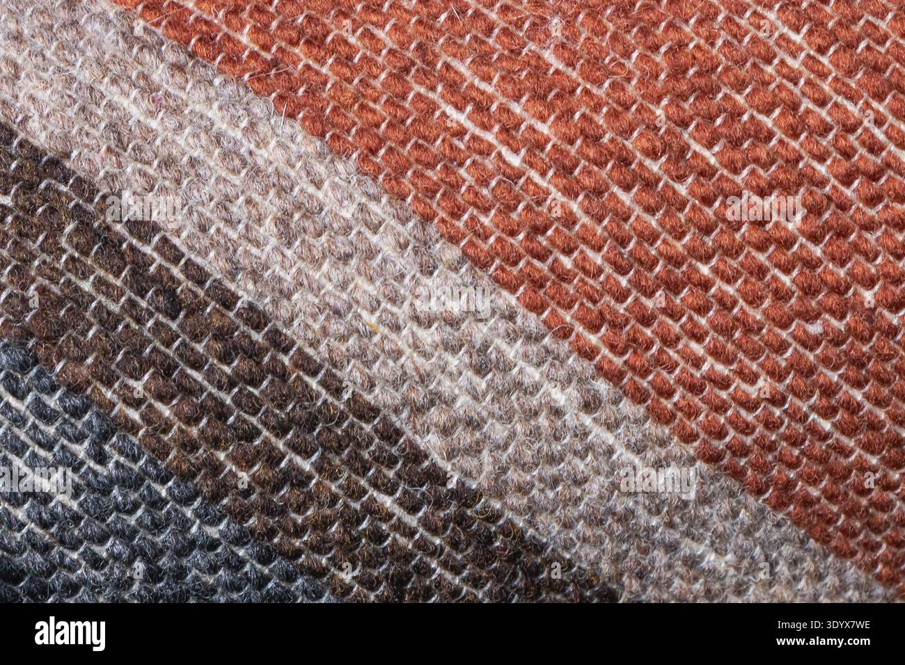 Makroaufnahme aus gewebtem Textilgewebe mit diagonalen Streifen in Braun-, Beige- und Cremetönen, die detaillierte Fasern und eine weiche Stoffstruktur zeigen. Stockfoto