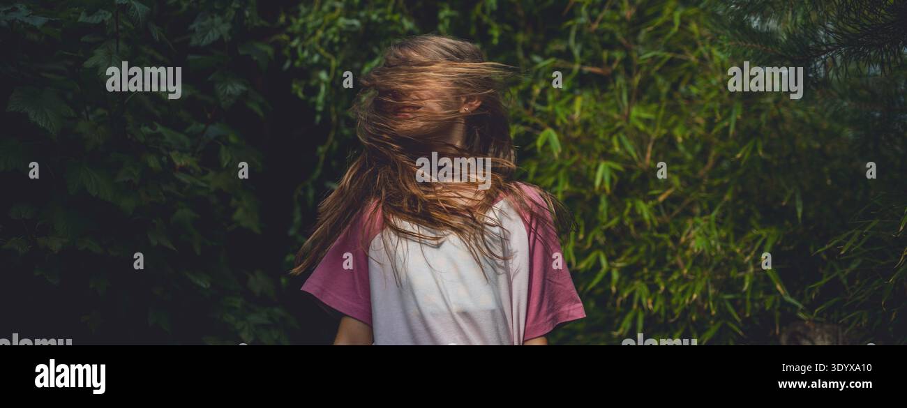 Sorgloses Mädchen, das sich im Garten während des warmen Sommertages dreht. Stockfoto