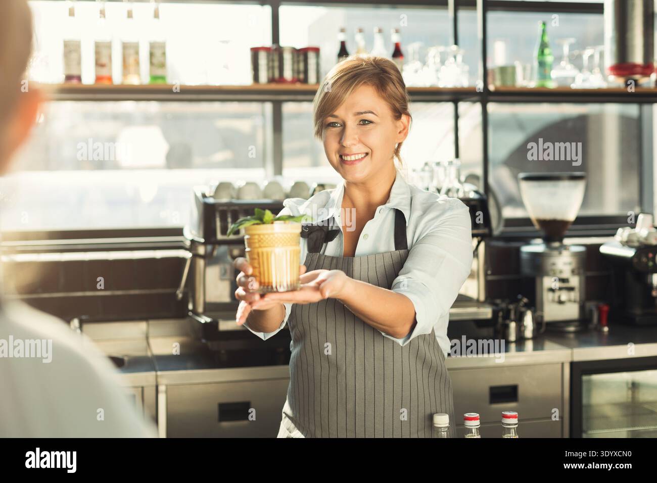 Glücklicher Barkeeper, der am Café-Theke Kaffee-Cocktail gibt Stockfoto