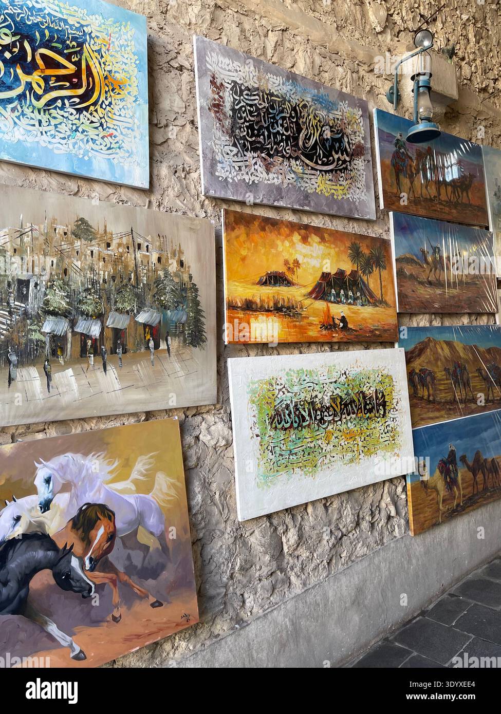 Traditionelle arabische Gemälde und Kunstwerke, die an einer Wand im Souq Waqif Market in Doha, Katar, ausgestellt werden - Smartphone-aufgenommenes Stockfoto