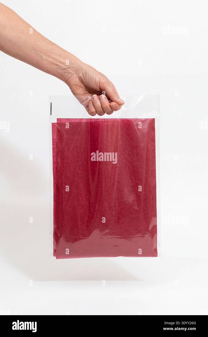 Modell einer durchsichtigen Plastiktüte mit einem Griff, der von einer Hand gehalten wird und rotes Papiertaschentuch enthält. Stockfoto