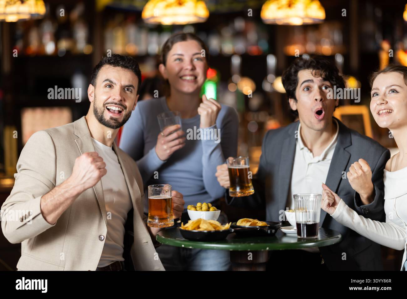 Glückliche Freunde feiern den Sieg ihrer Lieblingsteams, während sie sich das Spiel im Pub ansehen Stockfoto