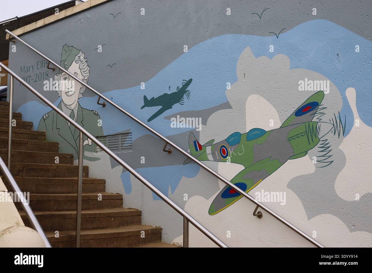 Eine schmale Treppe hinunter zwischen zwei Esplanadengebäuden feiert ein Wandgemälde das Leben der ATA Ferry Pilotin Mary Ellis (geb. Wilkins) aus dem Zweiten Weltkrieg. Stockfoto