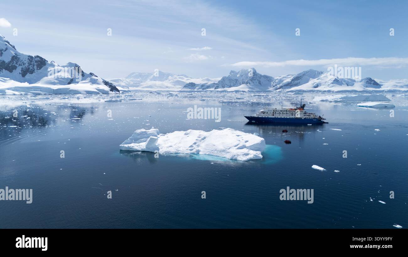 Ein Expeditionskreuzfahrtschiff treibt in der Nähe eines Eisbergs, während Passagiere in Zodiac-Schlauchbooten in der Nähe kreuzen. Argentinische Stirn Stockfoto