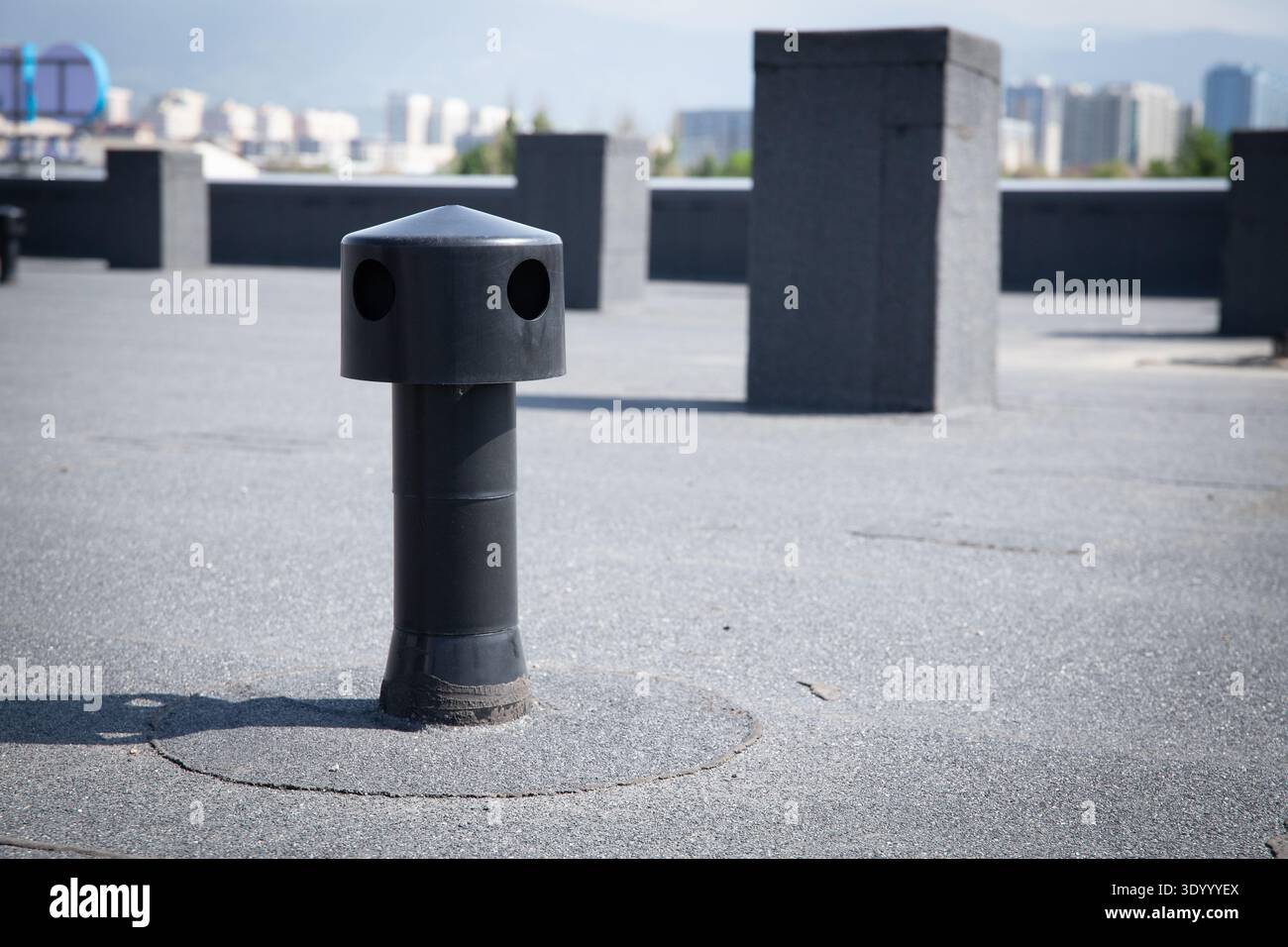 Schwarzer Dachbelüfter auf Bitumenoberfläche Stockfoto