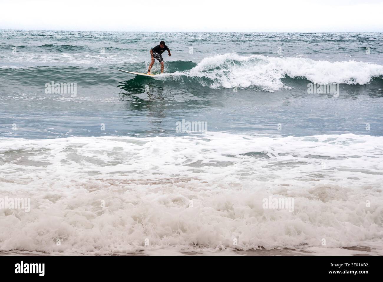 Surfer auf einer Welle in Crackington Haven an der Nordküste von Cornwall, Großbritannien Stockfoto