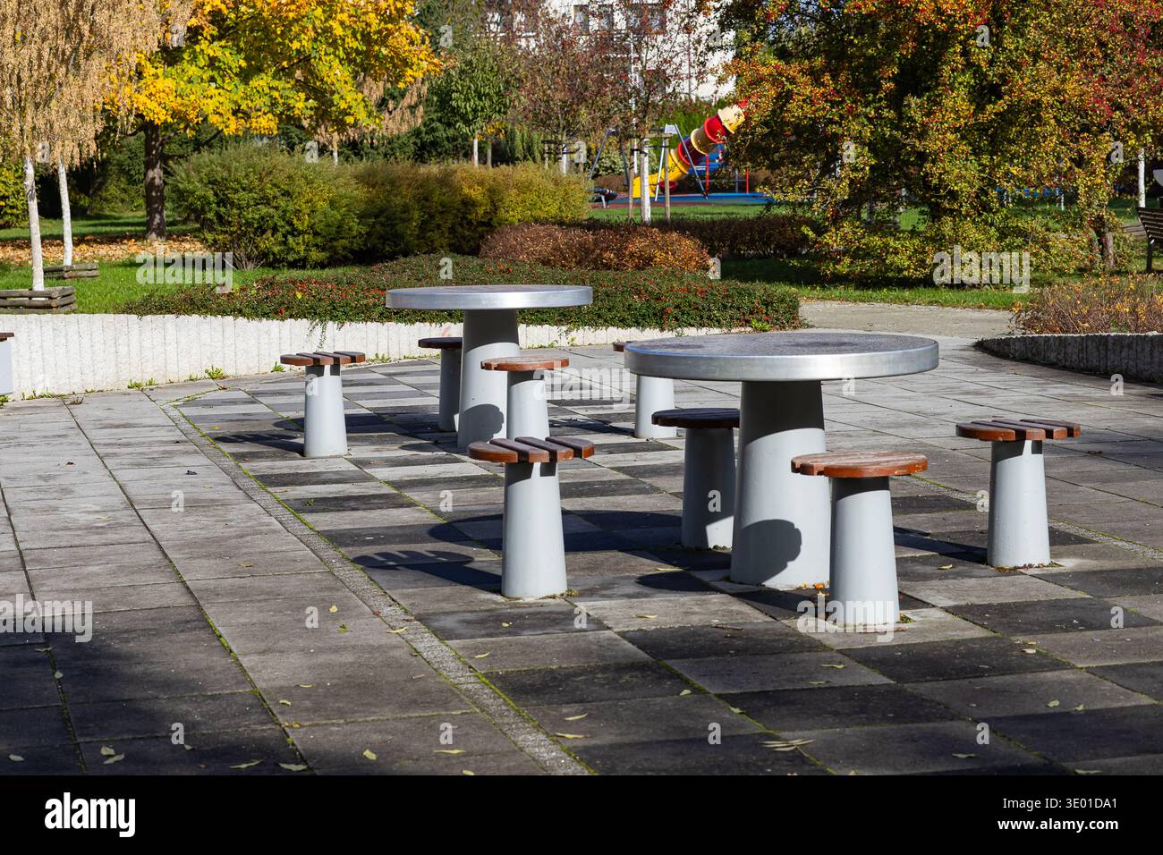 Erholungsbereich im Freien mit zugänglichen Betontischen und -Hockern in einem ruhigen Herbstpark für Senioren. Komfortable urbane Möbel Stockfoto