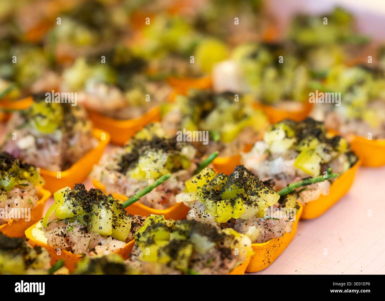 Gourmet-Fisch-Tartar-Vorspeise mit Gurke, Mayonnaise und Kräutern, serviert in mundgerechten Gebäckbechern. Elegantes Canapé mit Meeresfrüchten und gehacktem Fischtatar. Stockfoto
