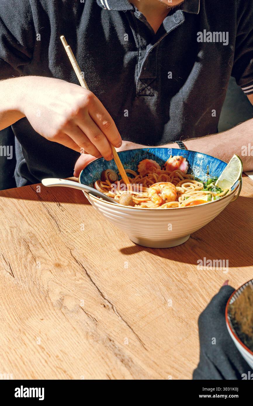 Mann isst Ramen mit Stäbchen. Professionelle Studio-Leuchte Stockfoto