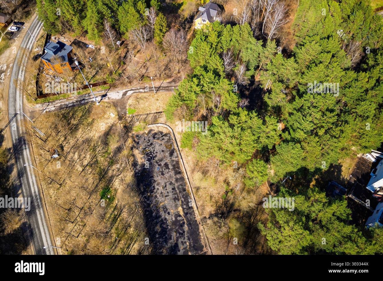 Blick aus der Drohne auf eine malerische ländliche Umgebung mit lebhaften immergrünen Wäldern, geschwungenen Straßen und einer offenen, parkähnlichen Weite im Sonnenlicht Stockfoto