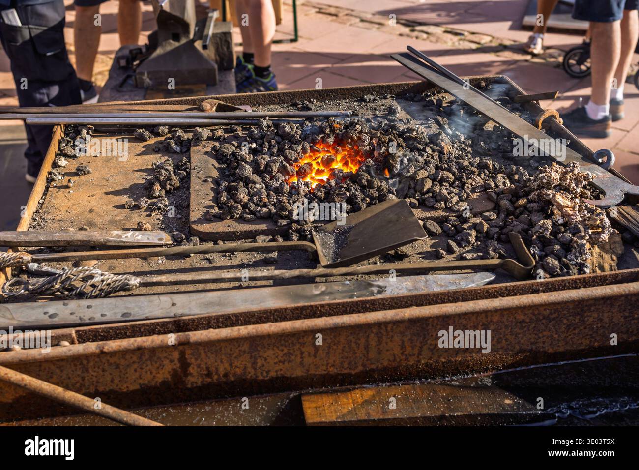 Glühende orangefarbene Kohlekohle in einer Schmiedeschmiede. Schmiedeofen mit Funken und Feuer auf dem lokalen Markt Stockfoto