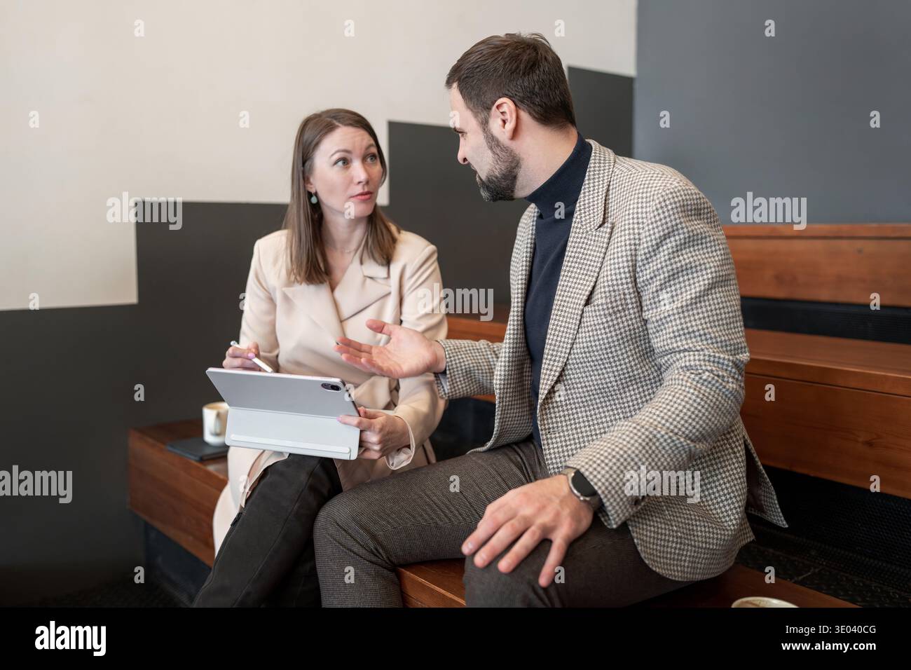 Teammitglieder, die das Meeting beenden und ein freundliches Gespräch auf einer hölzernen Bürobank führen. Beenden von Besprechung, Konversation, Büro, Teamarbeit, Arbeitsbereich. Stockfoto
