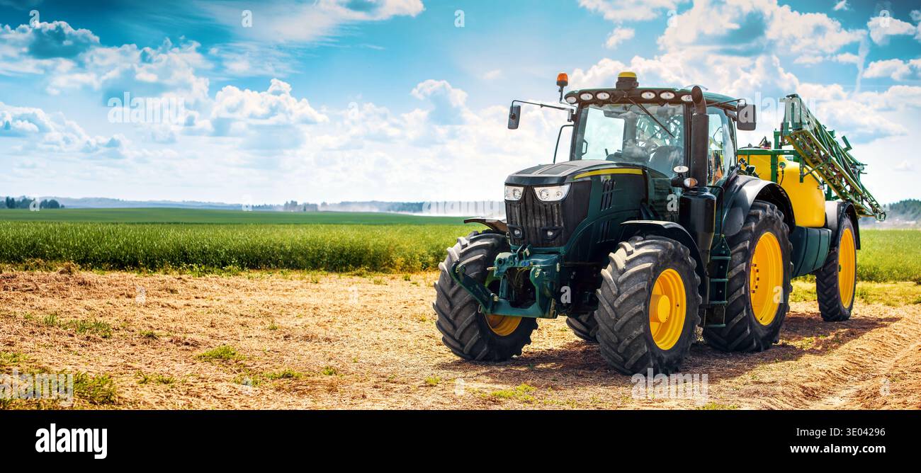 Moderner Traktor mit Spritzauflieger neben dem Ackerfeld. Banner mit Kopierbereich Stockfoto