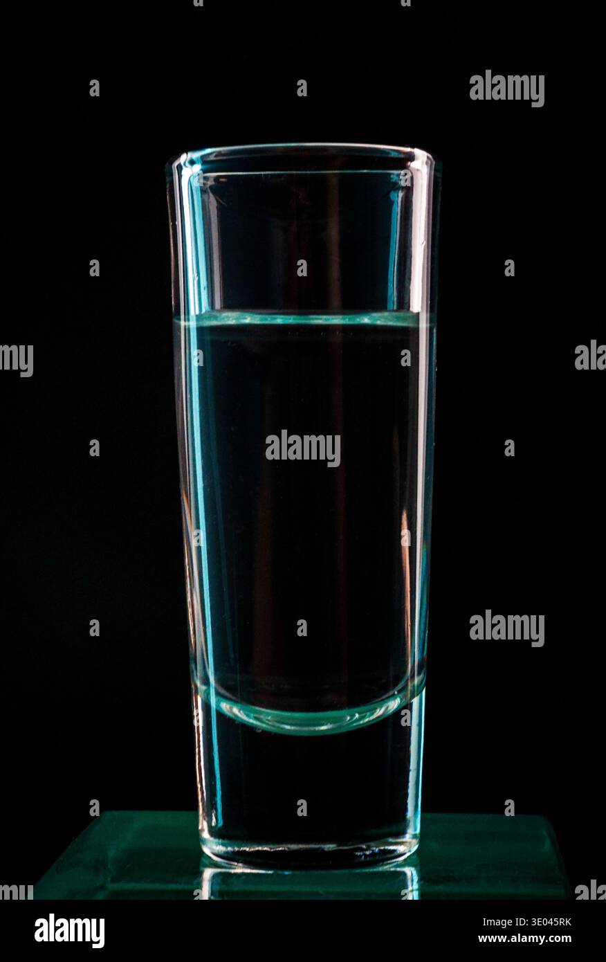 Glas Wasser auf schwarzem Hintergrund, minimale Fotografie mit dramatischem Blitz Stockfoto