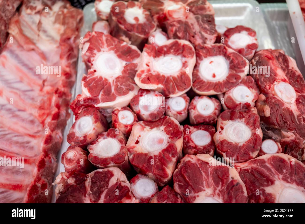 Eine Auswahl an frischem rohem Fleisch, das in einer Metzgerei ausgestellt wird, mit wunderschönen marmorierten Stücken. Diese Schnitte sind perfekt für den kulinarischen Einsatz und heben hervor Stockfoto