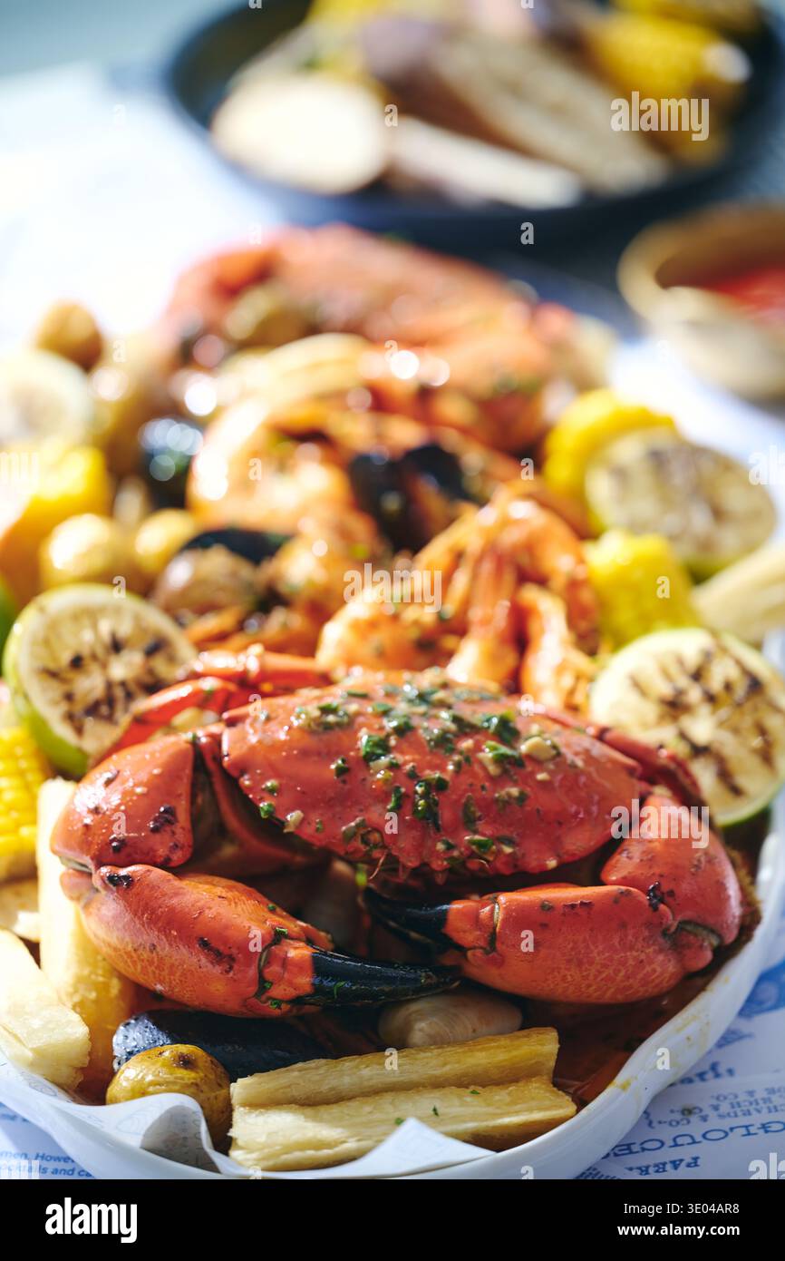 Eine lebendige Meeresfrüchte-Platte mit einer ganzen Krabbe, prallen Garnelen und verschiedenen Muscheln, wunderschön auf einem rustikalen Tisch angeordnet, perfekt für eine gemeinsame fa Stockfoto