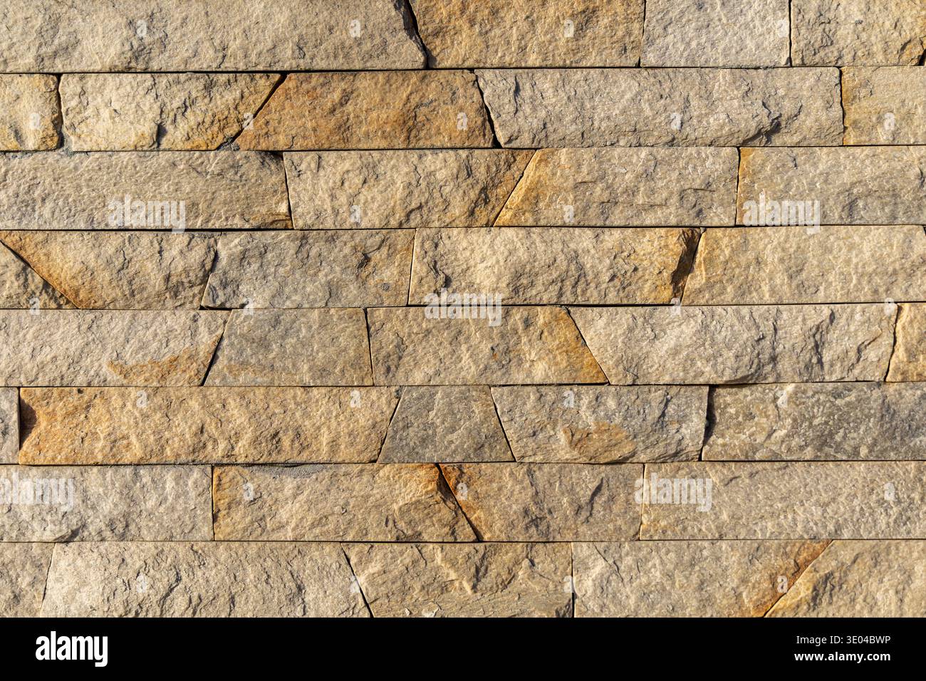 Beige Gestapelte Steinwand Textur Hintergrund. Nahaufnahme einer beigen gestapelten Steinmauer mit rauer natürlicher Textur, die eine dauerhafte Architektur schafft Stockfoto