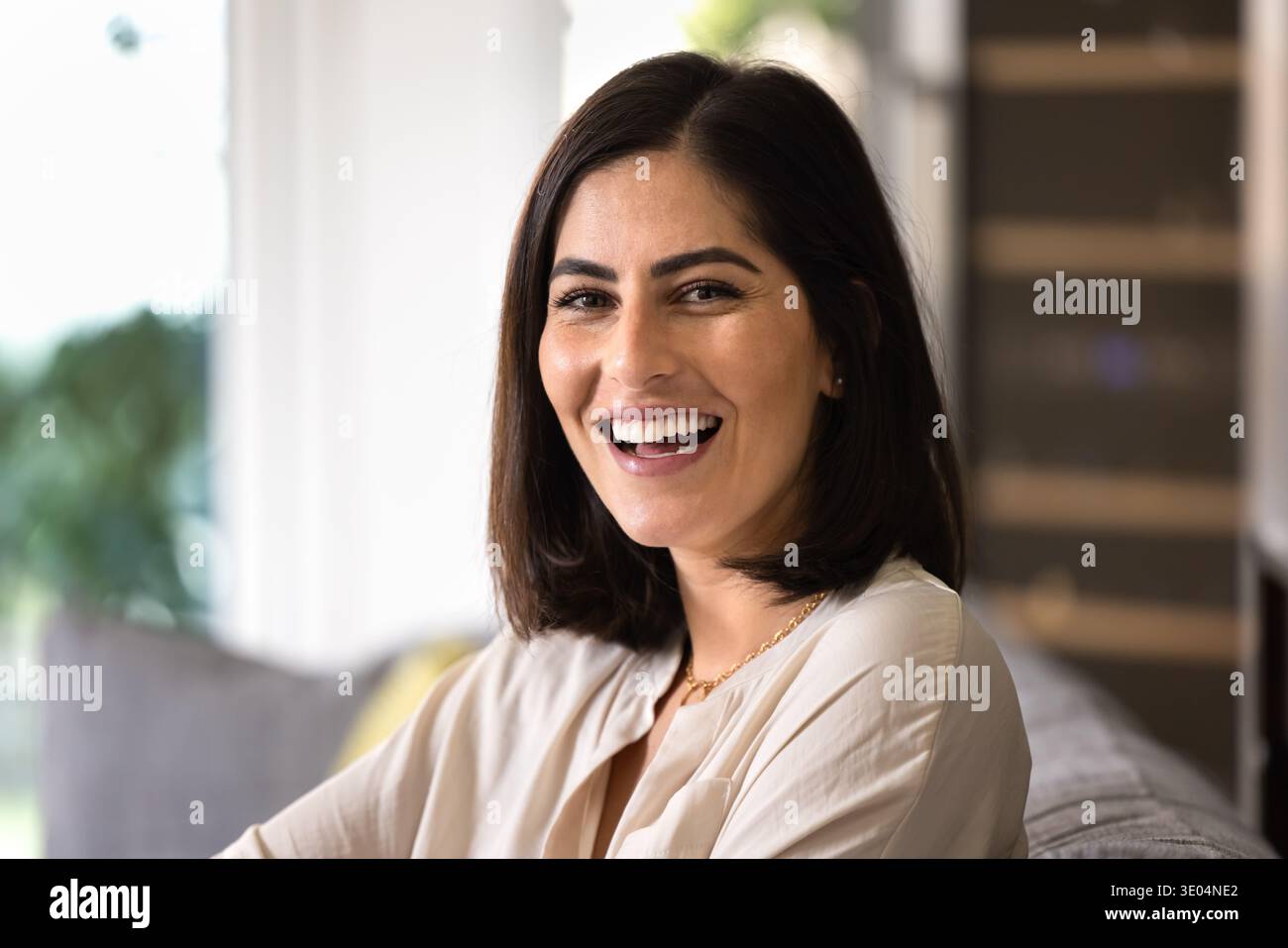 Fröhlich schöne brünette junge Lateinfrau posiert zu Hause Stockfoto