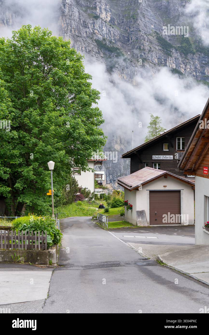 Alpine Dorfstraße mit hölzernen Chalets und nebeligen Bergen Stockfoto