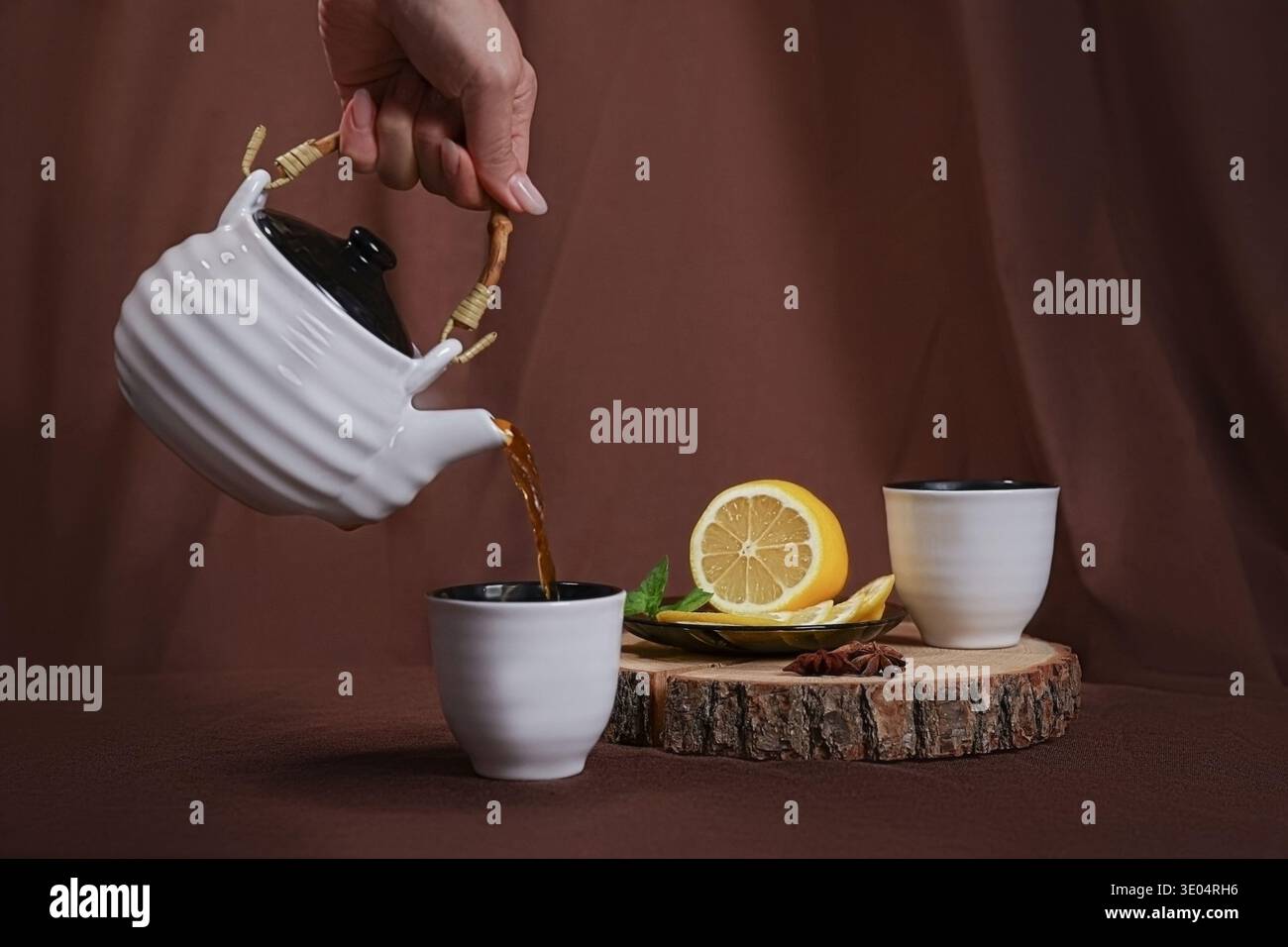 Hand gießt Tee für zwei Personen Stockfoto