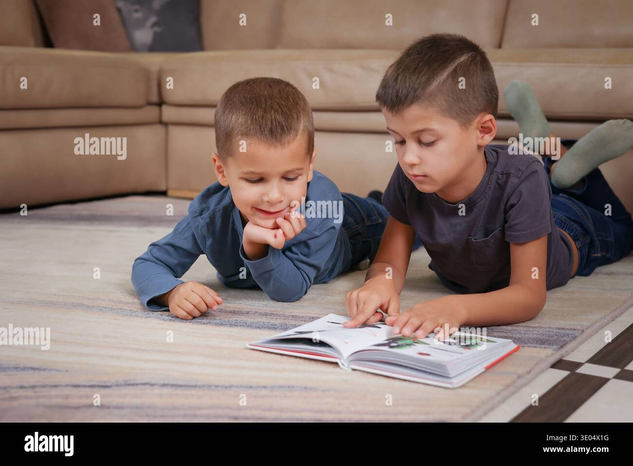 Zwei Brüder liegen auf dem Boden und lesen ein Buch Stockfoto