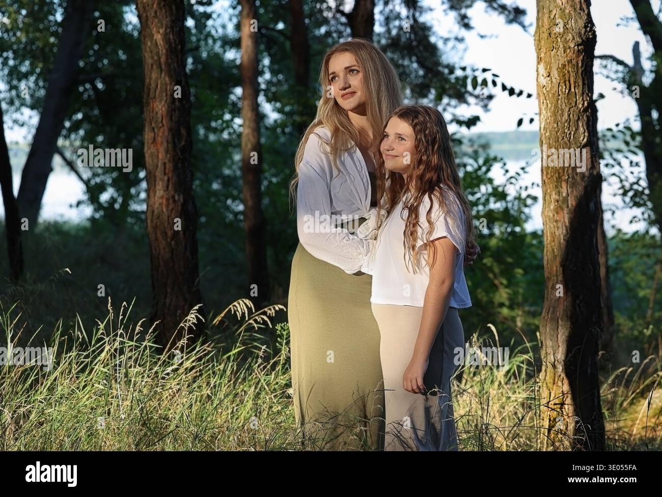 Schwestern im Wald stehen und schauen auf die Sonne Stockfoto