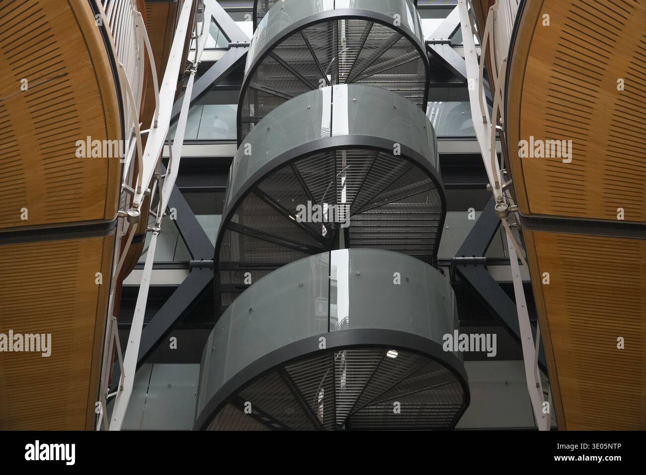 Die modernen Luxus-Apartments verfügen über eine markante Wendeltreppe aus Metall mit Milchglaspaneelen, klaren Linien und Holzverkleidungen. Stockfoto