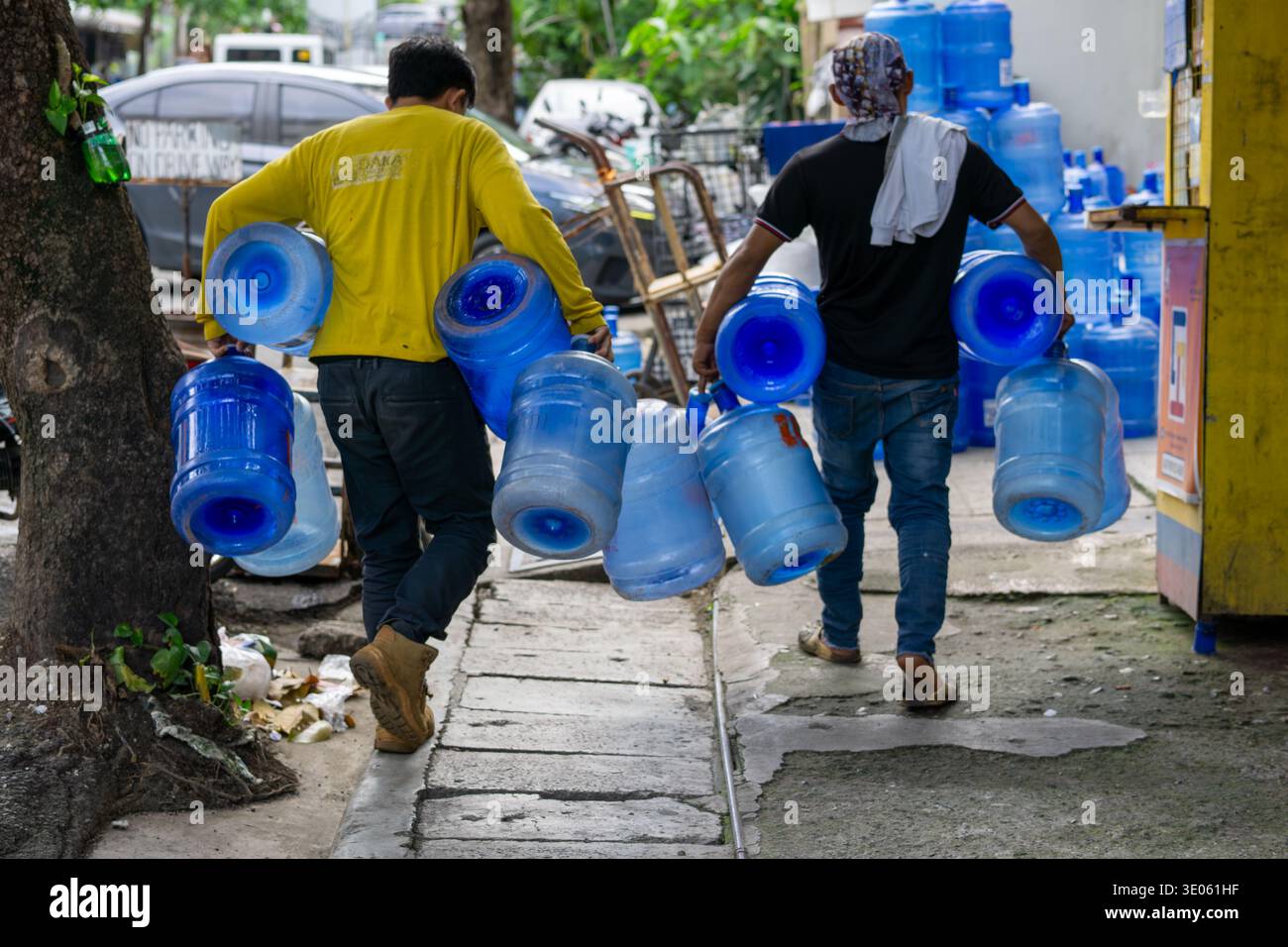 Wasserverkäufer bringen leere nachfüllbare Trinkwasserbehälter zu einer örtlichen Reinigungsstation in Cebu, Philippinen, auf die sich viele Bewohner verlassen. Stockfoto