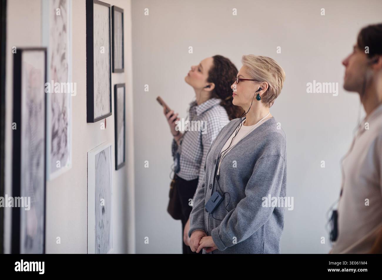 Kaukasierin mittleren Alters, die Kunstwerke in der Galerie mit Audioguide beobachtet Stockfoto