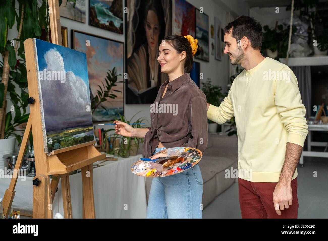 Glückliches verheiratetes Paar genießt Kunst, Frau arbeitet an Ölmalerei Ehemann lobt und unterstützt Ehefrau. Stockfoto