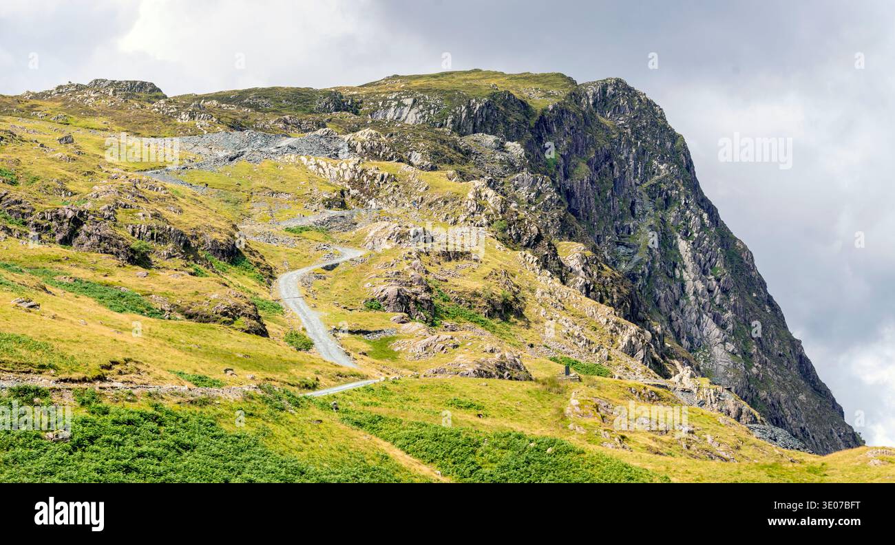 Dramatische Landschaft mit steiler kurviger Straße, die an einem warmen, sonnigen Mittsommertag einen felsigen Berg von Cumbrian hinaufführt. Stockfoto
