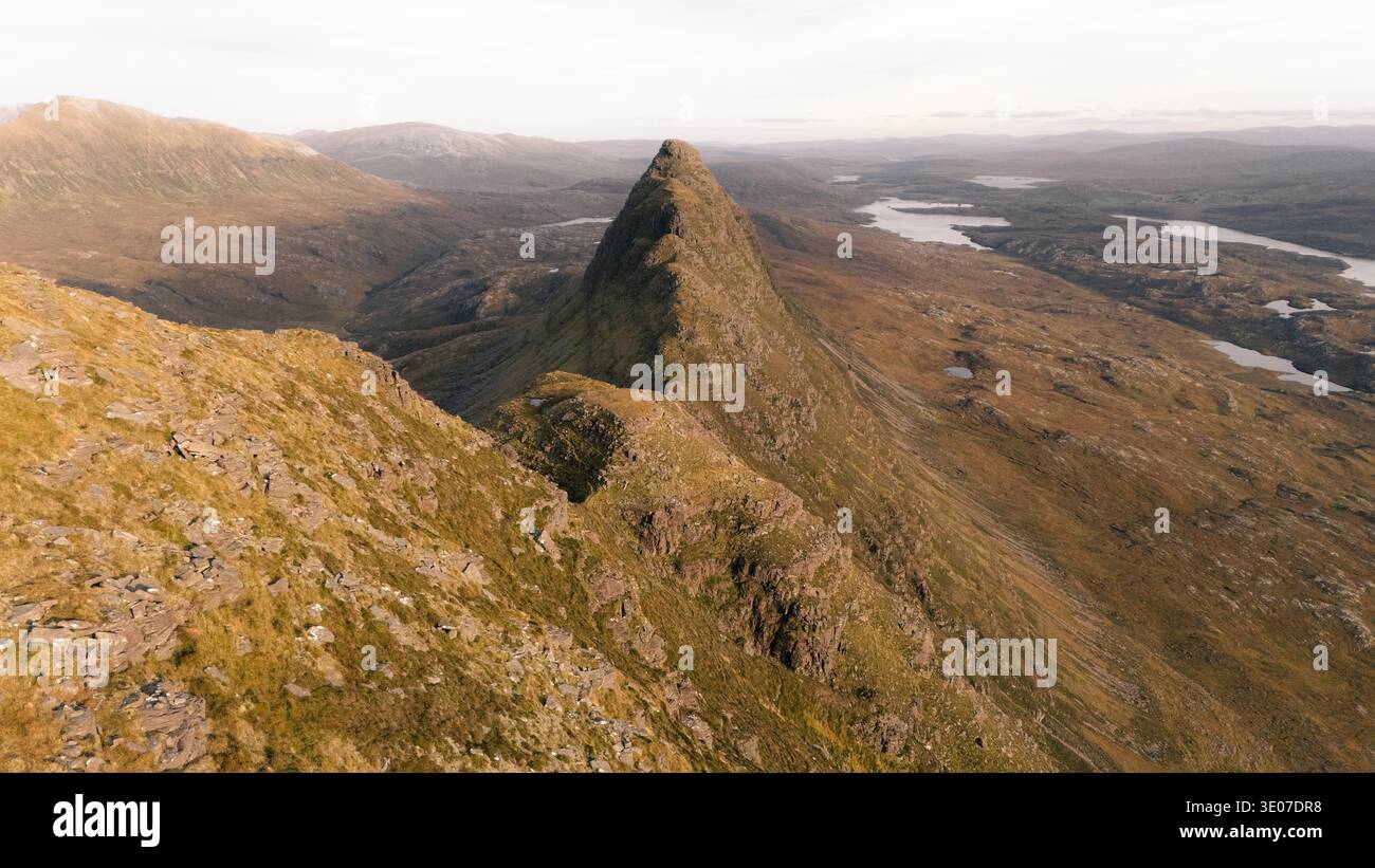 Der schroffe Gipfel des Suilven Mountain erhebt sich aus der Vogelperspektive scharf gegen die weitläufige, strukturierte Landschaft, eine Symphonie aus Erdtönen, die mit dem dist kontrastiert Stockfoto