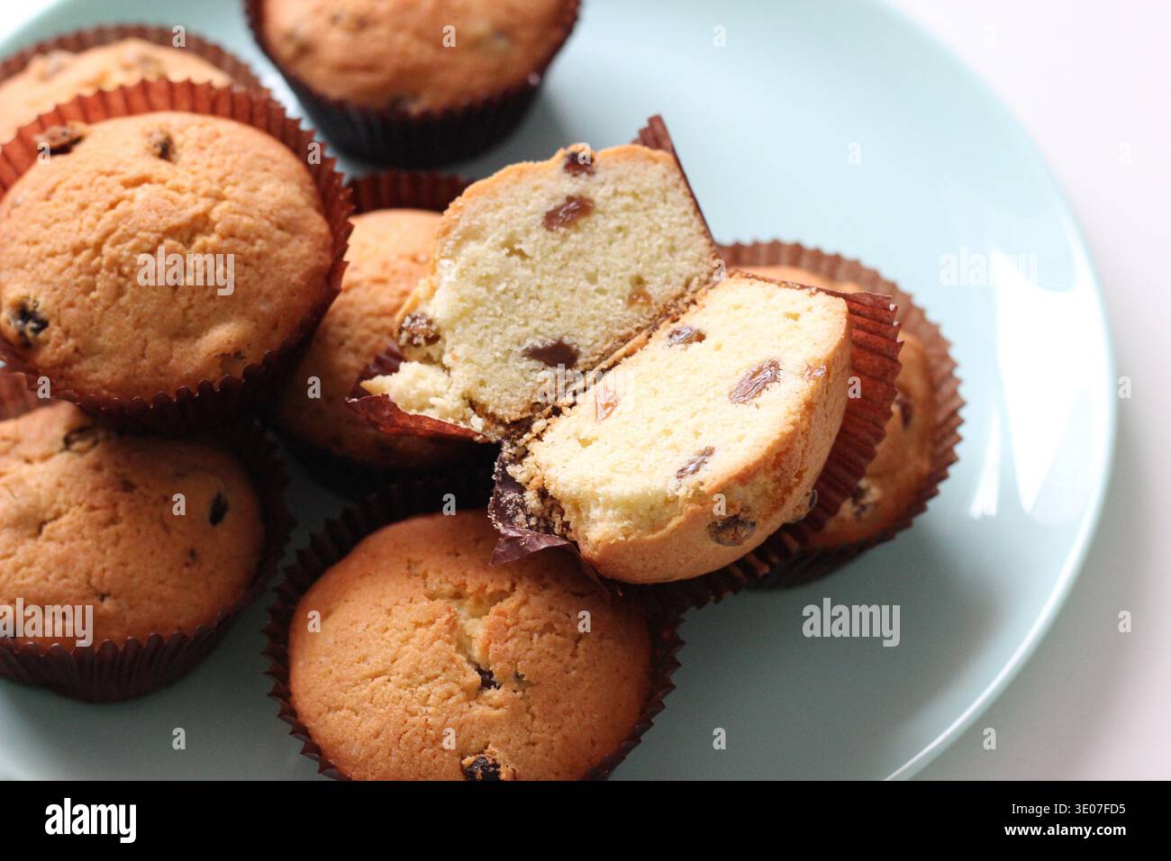 Nahaufnahme von hausgemachten Rosinenmuffins mit einem in Scheiben geschnittenen Muffin mit zarten Krume und Rosinen, frisch gebackenem Gebäck in Papiereinlagen Stockfoto