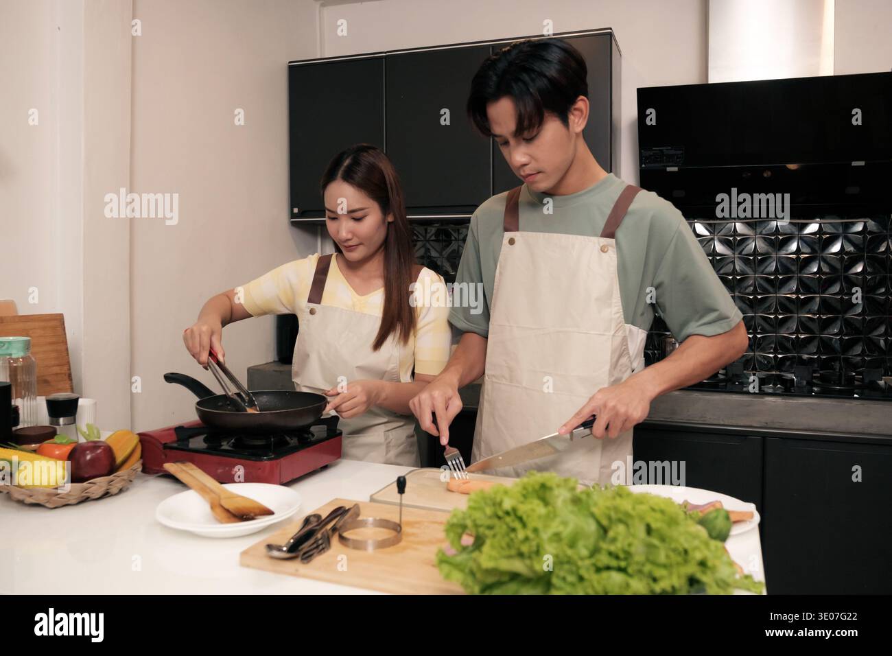 Asiatisches junges Paar, das in der Küche zu Hause kocht Stockfoto