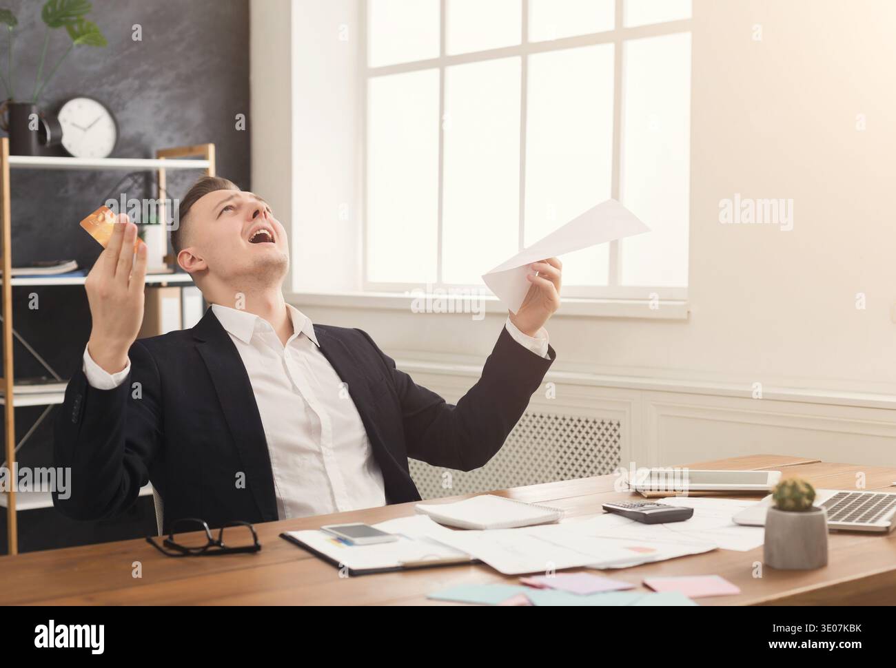 Junger, trauriger Geschäftsmann im Büro mit Rechnungen Stockfoto