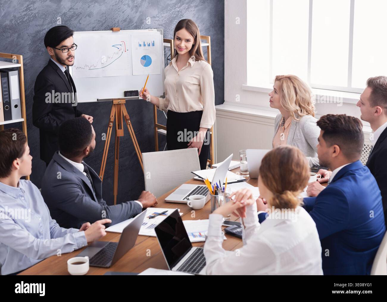 Kollegen zeigen Diagramme auf flipboard im Büro Stockfoto