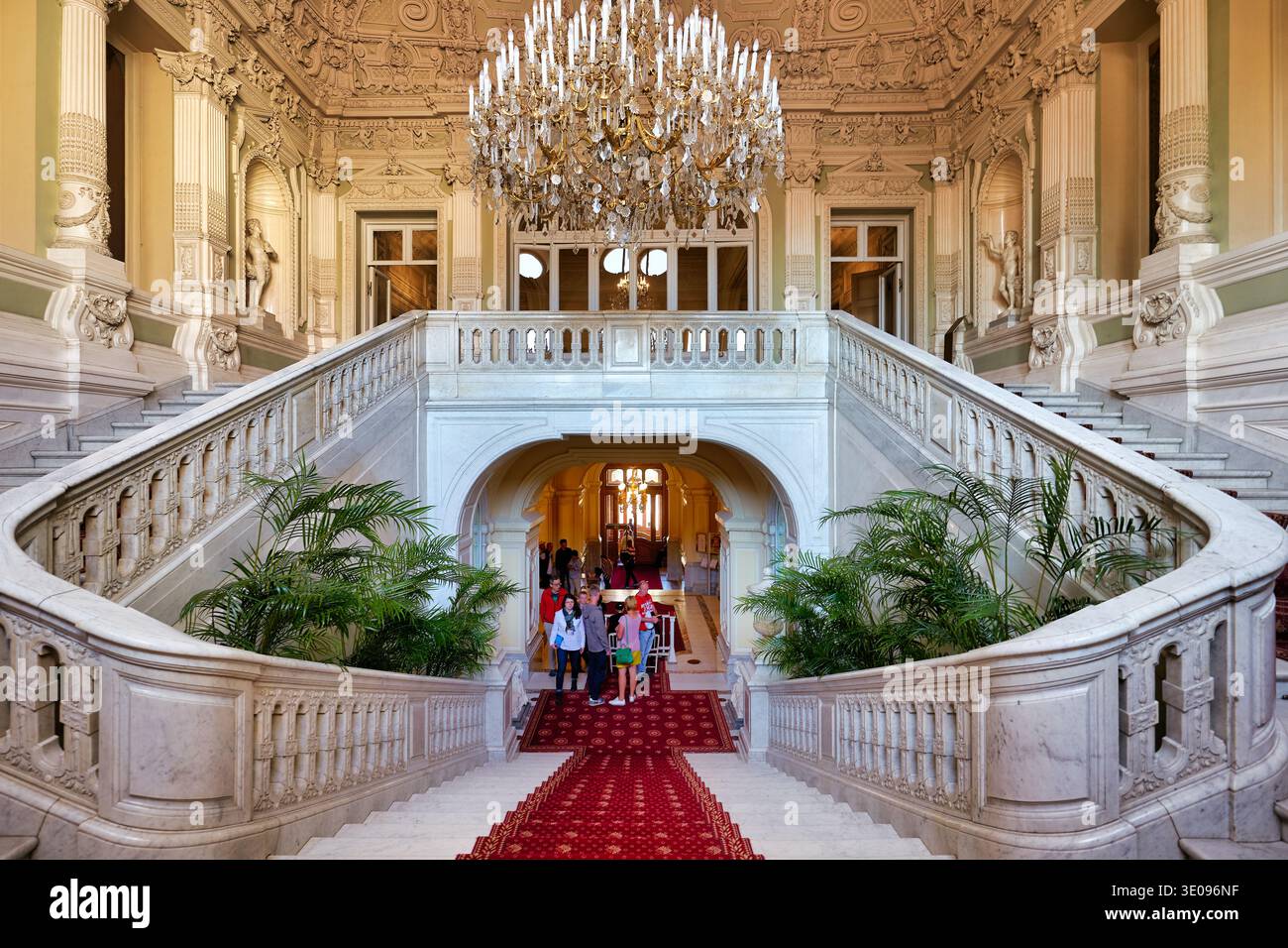 Die Leute gehen die große Treppe im Yusupow-Palast in St. Petersburg hinunter. Der Palast verfügt über einen großen Kronleuchter und Dekorationen. Stockfoto