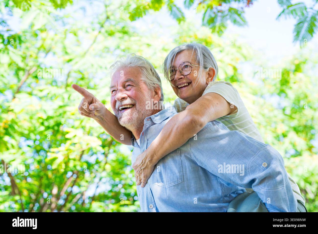 Zwei glückliche und fröhliche ältere, alte Männer, die auf dem Rücken seiner Frau herumliegen und zusammen lachen. Ein liebevolles, altes Familienpaar, das sich umschließt, Fee Stockfoto