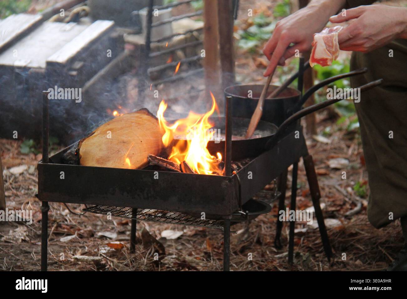 Kochspeck in einer Pfanne auf einem Holzfeuer im Freien. Stockfoto