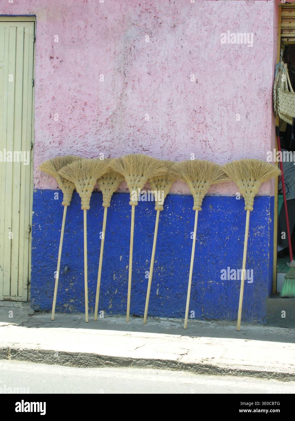 Farbenfrohe pinkfarbene und blaue Wände und handgefertigte Strohbesen. Stockfoto